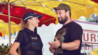 Eine Polizistin spricht mit einem Händler auf einem Markt